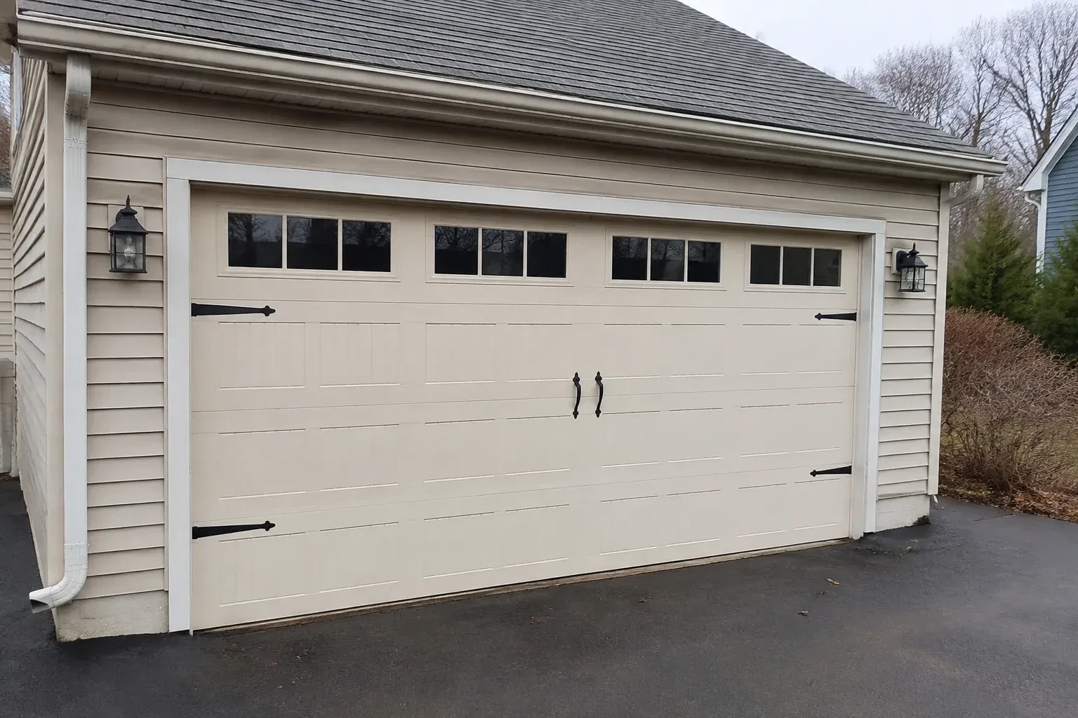 Cream carriage-house-style garage door with dark decorative hardware. — Carriage-House Garage Door Installation, Wilmot
