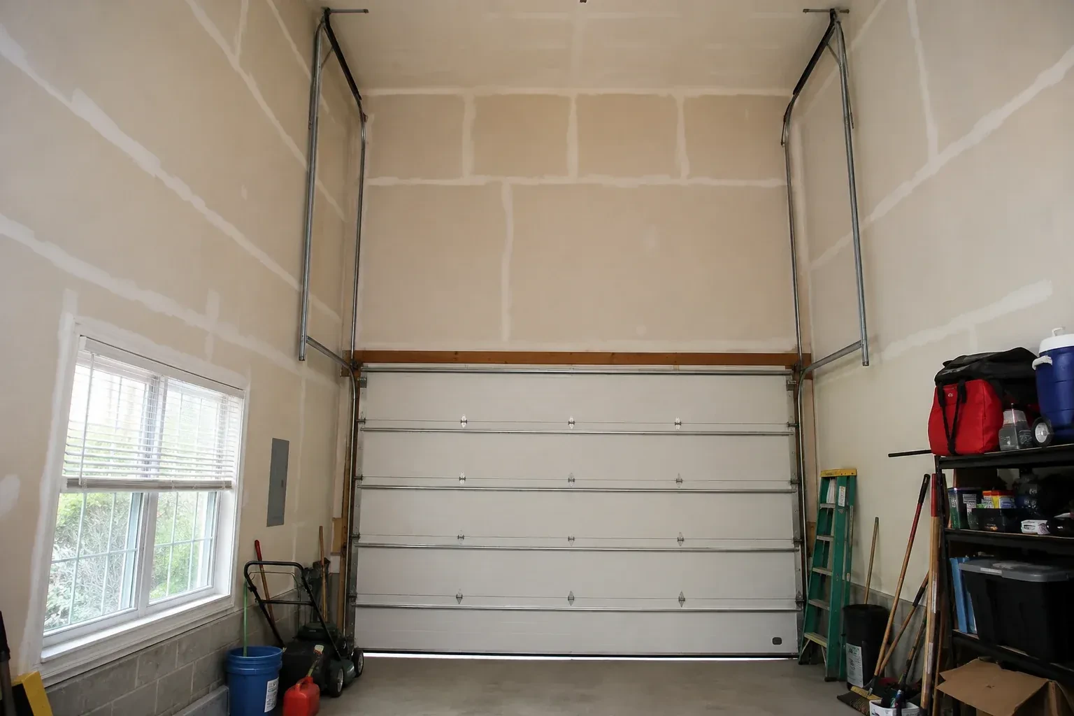Tall garage interior with a sectional door and tracks extending into overhead space. — High-Lift Garage Door Conversion, Wilmot